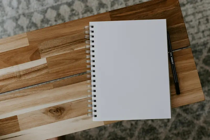 Blank spiral notebook and pen on a wooden desk