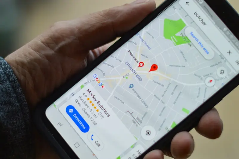 Hand holding a phone showing a business listing on Google Maps